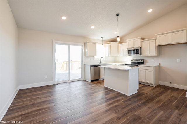 kitchen with a center island, hanging light fixtures, dark hardwood / wood-style flooring, white cabinets, and appliances with stainless steel finishes