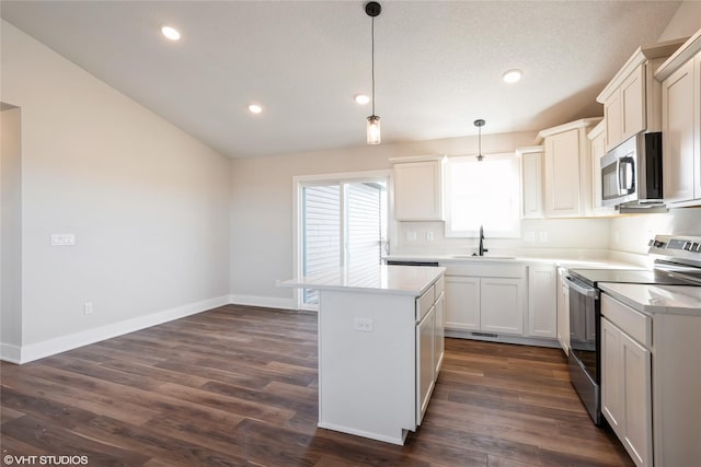 kitchen featuring sink, dark hardwood / wood-style flooring, hanging light fixtures, and appliances with stainless steel finishes