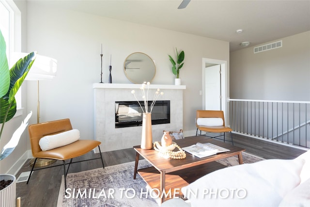 living room with a tiled fireplace and dark wood-type flooring