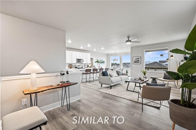 living room with ceiling fan and light hardwood / wood-style floors