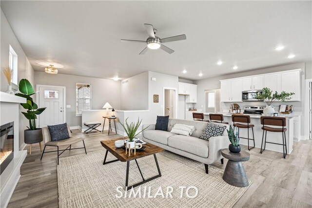 living room featuring ceiling fan, plenty of natural light, and light hardwood / wood-style flooring