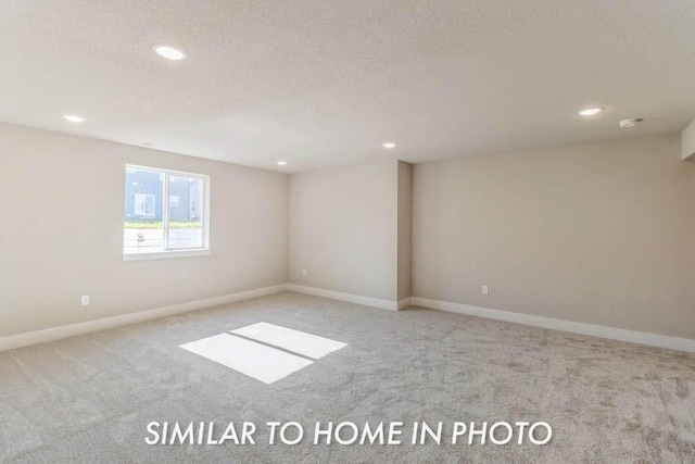 empty room with light colored carpet and a textured ceiling