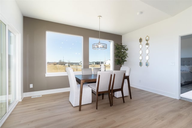 dining room with a chandelier, light wood-type flooring, visible vents, and baseboards