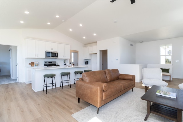 living area with lofted ceiling, recessed lighting, a ceiling fan, visible vents, and light wood-style floors