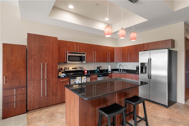 kitchen featuring a raised ceiling, a kitchen island, stainless steel appliances, and a textured ceiling