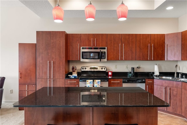 kitchen featuring appliances with stainless steel finishes, dark stone counters, pendant lighting, and sink