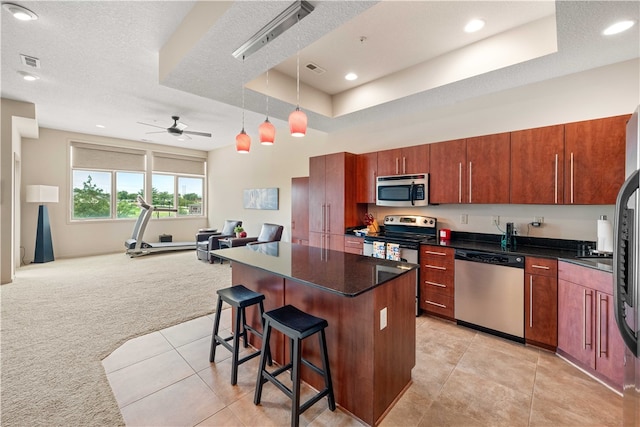 kitchen with a kitchen breakfast bar, ceiling fan, a textured ceiling, light colored carpet, and stainless steel appliances