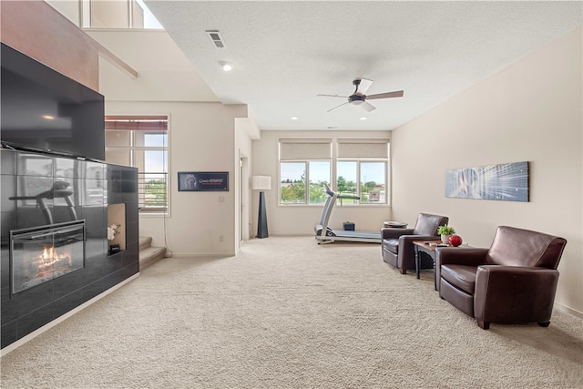 living room featuring a tile fireplace, carpet floors, and plenty of natural light