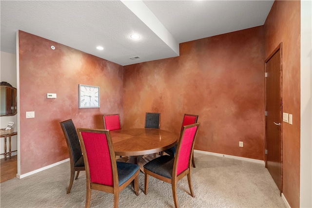 dining space featuring a textured ceiling and light carpet