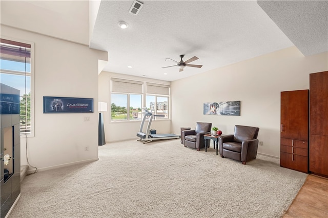 sitting room with ceiling fan, light carpet, and a textured ceiling