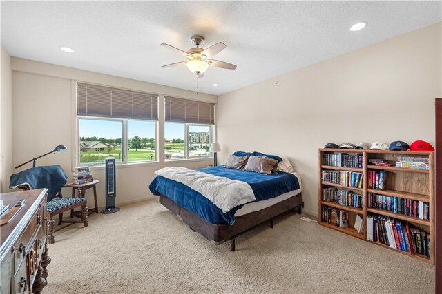 bedroom featuring a textured ceiling, light colored carpet, and ceiling fan