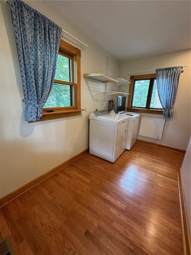 clothes washing area with washer and dryer and light hardwood / wood-style flooring