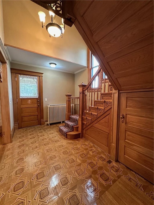 foyer entrance with radiator heating unit, crown molding, and wooden walls