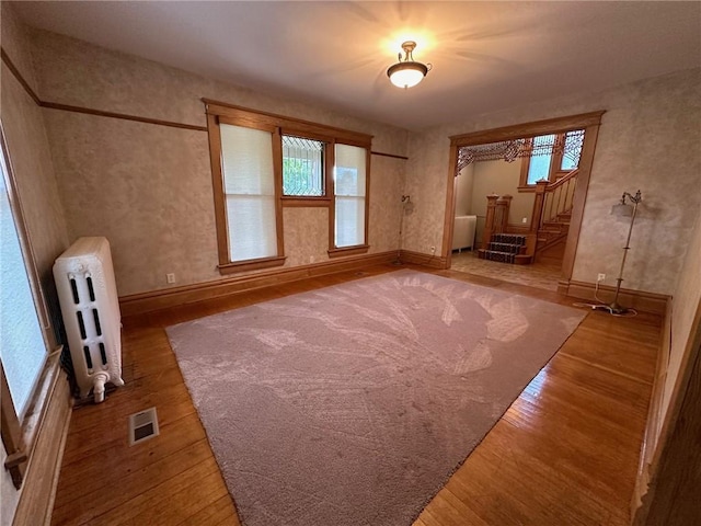 interior space with wood-type flooring and radiator heating unit