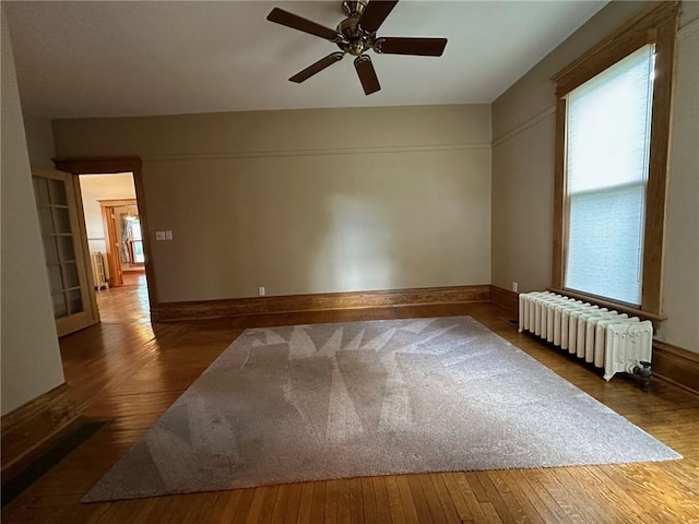 unfurnished room featuring ceiling fan, hardwood / wood-style floors, and radiator