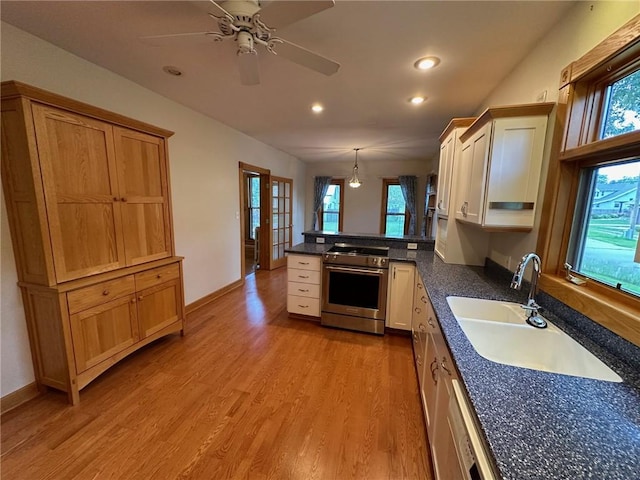 kitchen featuring high end stainless steel range oven, kitchen peninsula, decorative light fixtures, light hardwood / wood-style flooring, and sink