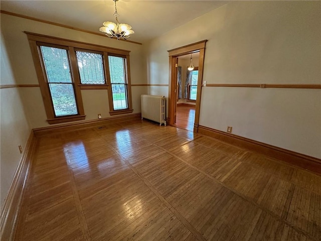 unfurnished room featuring plenty of natural light, radiator heating unit, and a chandelier