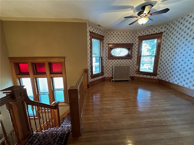 interior space with ceiling fan, wood-type flooring, radiator, and crown molding