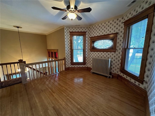 interior space featuring ceiling fan, wood-type flooring, radiator heating unit, and crown molding