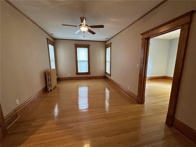 empty room with ceiling fan, radiator, ornamental molding, and light hardwood / wood-style flooring