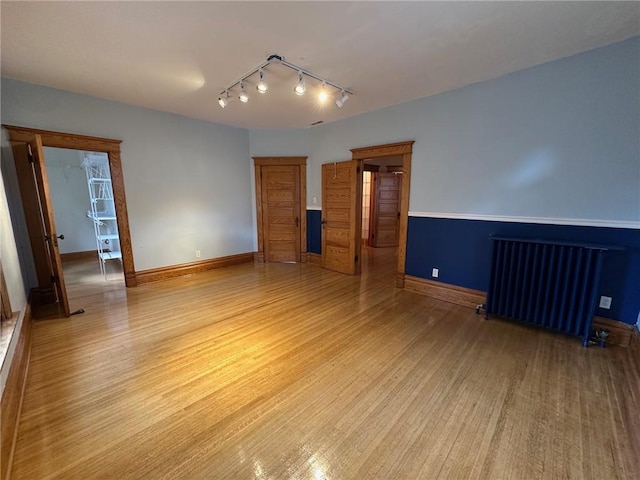 unfurnished room featuring radiator and light hardwood / wood-style flooring