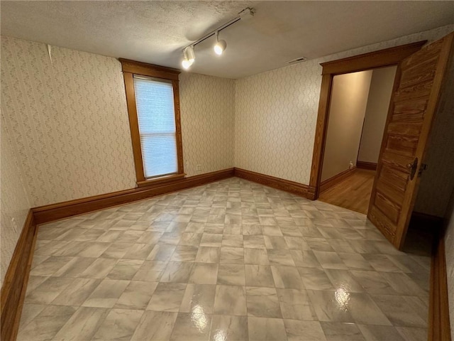 spare room featuring a textured ceiling and track lighting