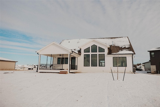 snow covered rear of property with ceiling fan and covered porch