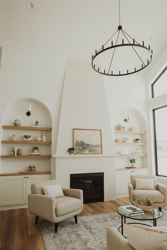 living room with hardwood / wood-style flooring, built in shelves, and a high ceiling