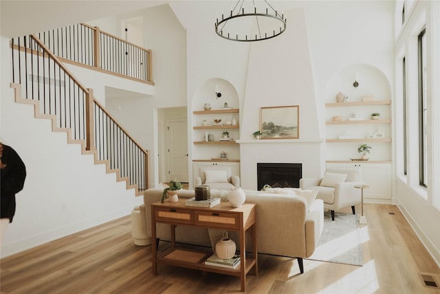 living room featuring built in shelves, light hardwood / wood-style floors, and a high ceiling