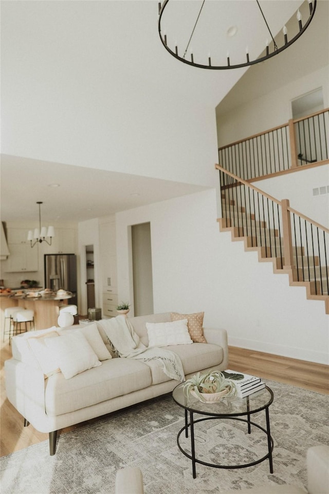 unfurnished living room with a towering ceiling, wood-type flooring, and a notable chandelier