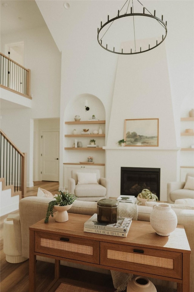 living room featuring built in shelves, a towering ceiling, and hardwood / wood-style flooring