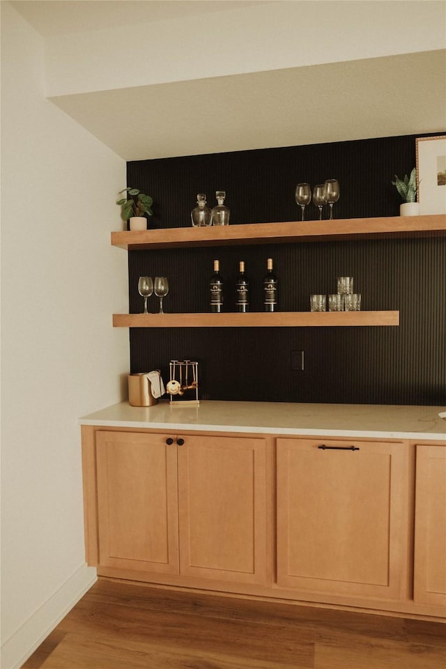 bar with light brown cabinetry and light wood-type flooring