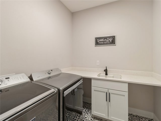 washroom featuring light tile patterned flooring, sink, washer and dryer, and cabinets