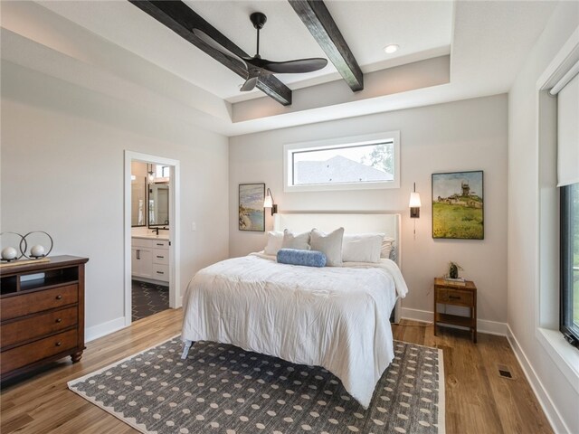 bedroom featuring ceiling fan, beamed ceiling, connected bathroom, and wood-type flooring