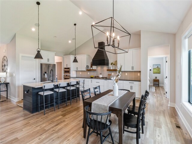 dining space with an inviting chandelier, light hardwood / wood-style flooring, and high vaulted ceiling