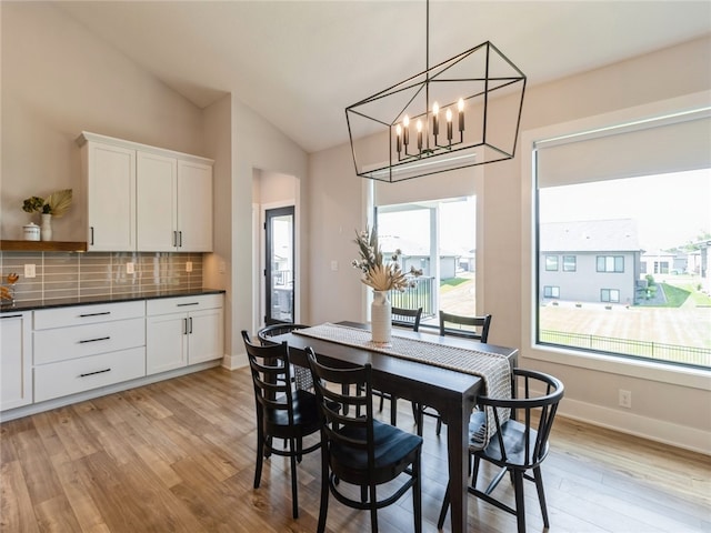 dining area with light hardwood / wood-style flooring, lofted ceiling, and a chandelier