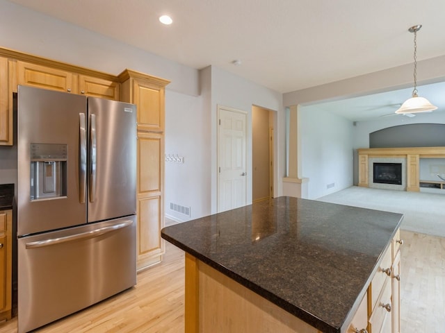 kitchen featuring a center island, visible vents, open floor plan, light brown cabinets, and stainless steel fridge