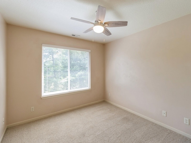 carpeted spare room featuring a ceiling fan, visible vents, a textured ceiling, and baseboards