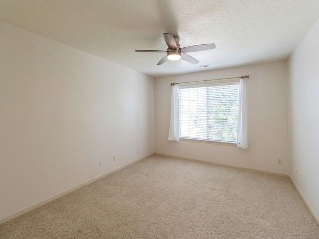 carpeted spare room featuring baseboards, ceiling fan, visible vents, and a textured ceiling