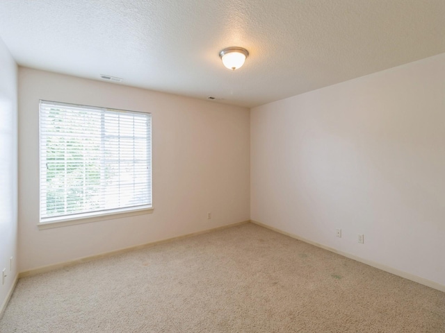 unfurnished room featuring baseboards, carpet, visible vents, and a textured ceiling