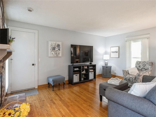 living room with light wood-type flooring and a brick fireplace