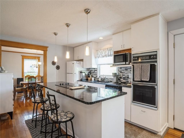 kitchen featuring white cabinetry, decorative backsplash, decorative light fixtures, black appliances, and sink