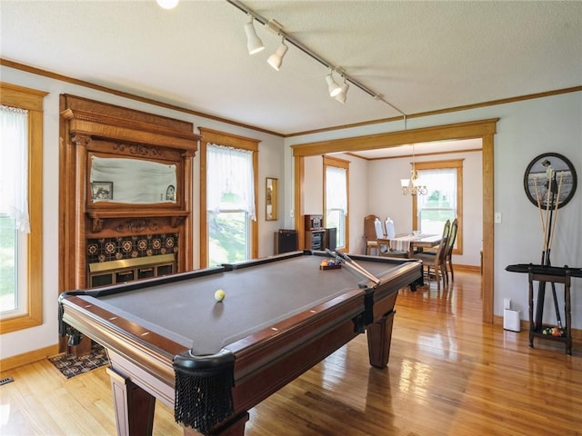 recreation room featuring light hardwood / wood-style floors, pool table, track lighting, ornamental molding, and a chandelier