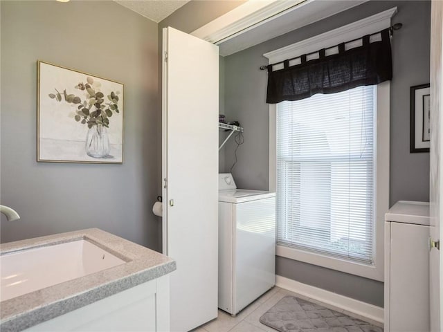 clothes washing area with sink, light tile patterned floors, and washer / clothes dryer