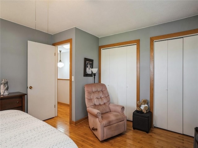 bedroom with two closets and light hardwood / wood-style floors