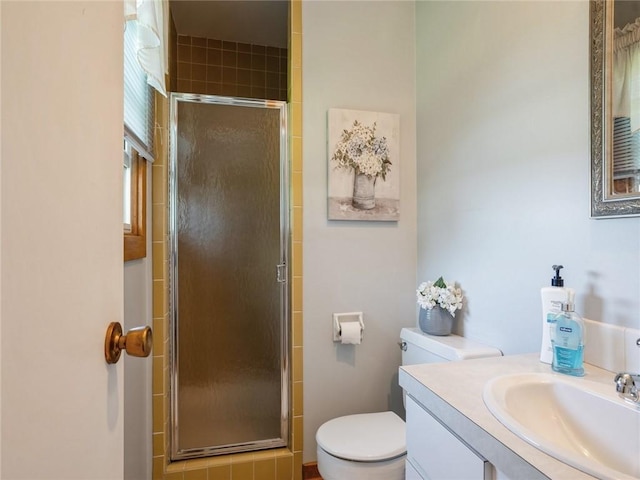 bathroom featuring toilet, a shower with shower door, and vanity