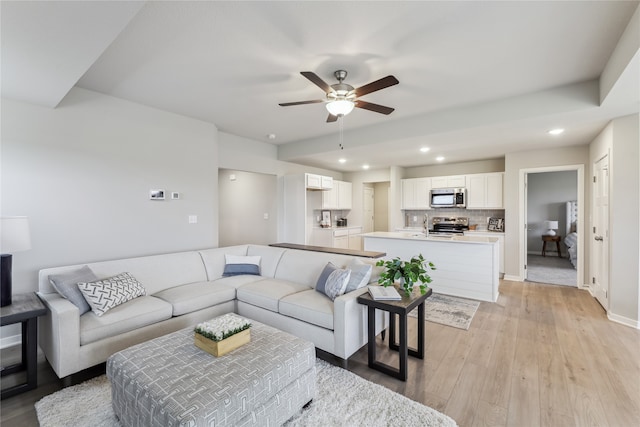 living room featuring ceiling fan, light hardwood / wood-style flooring, and sink