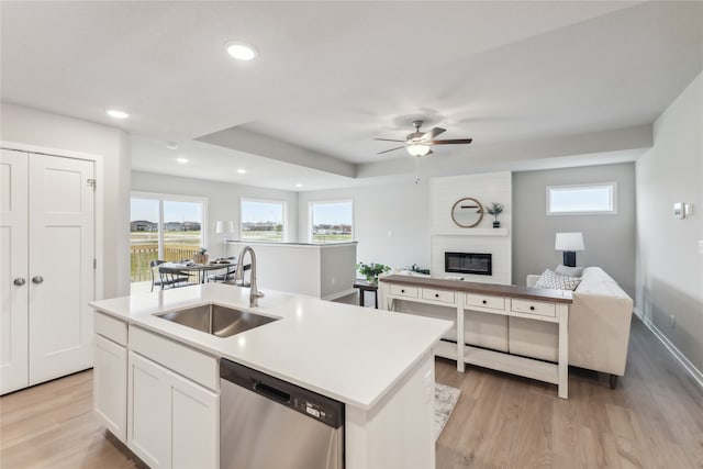 kitchen with sink, stainless steel dishwasher, an island with sink, white cabinets, and light wood-type flooring