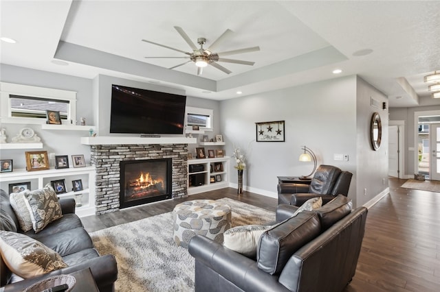 living room featuring a fireplace, dark hardwood / wood-style floors, ceiling fan, and a raised ceiling