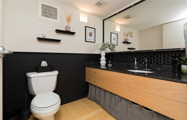 bathroom with hardwood / wood-style floors, backsplash, toilet, and vanity